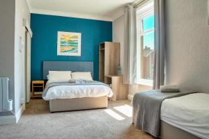 ein Schlafzimmer mit 2 Betten und einer blauen Wand in der Unterkunft Sandcliff Guest House in Cromer