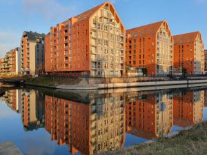 a group of brick buildings reflected in a body of water at MagSpace River View Jacuzzi Apartment in Gdańsk