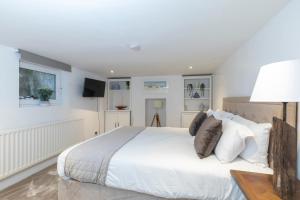 a white bedroom with a large bed and a lamp at Beautiful 4 Bedroom Home in Cheltenham