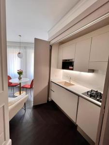 uma cozinha com armários brancos e uma mesa num quarto em Elegante appartamento in zona Tortona-Solari em Milão