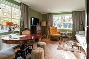 a living room with a table and a couch at Boetiekhotel De Kastanjehof in Lage-Vuursche