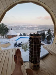 een persoon voeten op een tafel die uit een raam naar een zwembad kijkt bij Mergen Bike & Ski Resort in Niedzica Zamek