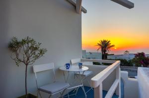 a balcony with a table and chairs and a sunset at Christina's Cave House in Fira