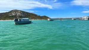 a boat sitting in the middle of a body of water at Kraalbaai Lifestyle House Boats in Langebaan