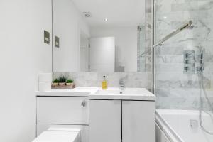 y baño blanco con lavabo y ducha. en Reading Town Centre 1 & 2 Bedroom Apartments with Parking by 360Stays, en Reading