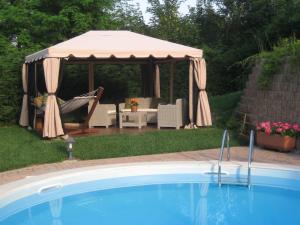 a gazebo with a table and chairs and a pool at B&B Castelvecchio in Ferrere