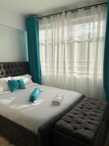 - un lit avec des oreillers bleus et une fenêtre dans l'établissement Zoe Homes Greypoint 1br and 2bedroom Apartment 301, à Kericho