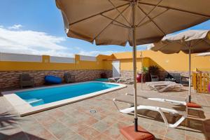 una piscina con sillas y sombrilla y una piscina en Casa Paco 2, en Costa Calma