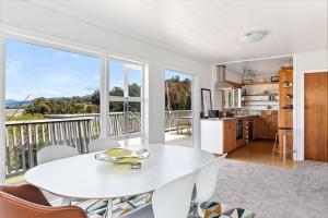 comedor blanco con mesa y balcón en Emily's Beach House - Kaiteriteri Holiday Home, en Kaiteriteri