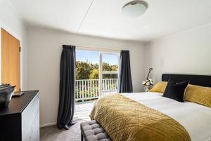 Un dormitorio con una cama grande y una ventana. en Emily's Beach House - Kaiteriteri Holiday Home, en Kaiteriteri