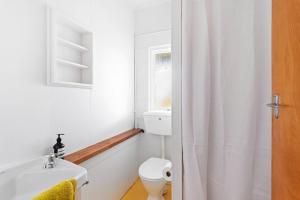 ein weißes Bad mit einem WC und einem Waschbecken in der Unterkunft Emily's Beach House - Kaiteriteri Holiday Home in Kaiteriteri