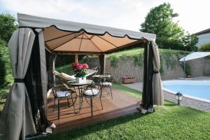 a gazebo with a table and chairs next to a pool at B&B Castelvecchio in Ferrere