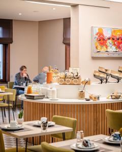 a restaurant with tables and people sitting at a counter at Hotel Olympia in Bruges in Bruges