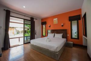 a bedroom with a large bed with an orange wall at The Blue Gecko in Ko Lanta