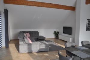 a living room with a gray couch and a tv at Schnurs Ferienwohnung in Römerberg