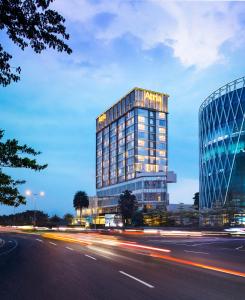 un edificio de cristal alto con luces frente a una calle en Atria Hotel Gading Serpong, en Serpong