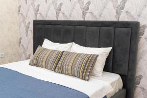 RentWill apartments Grey في كيشيناو: سرير مع اللوح الأمامي الأسود ومخدة