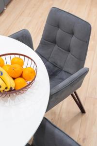 a bowl of oranges on a table with a chair at RentWill apartments Grey in Chişinău