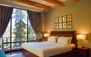 ein Schlafzimmer mit einem Bett und einem großen Fenster in der Unterkunft Lemon Lodges By Roomy, Nathiagali in Nathia Gali