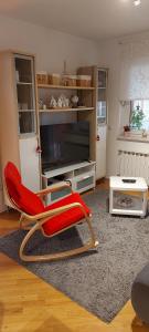 uma sala de estar com uma cadeira vermelha em frente a uma televisão em Apartment 40 em Zagreb