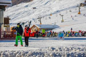 due persone in piedi nella neve vicino a una pista da sci di Italia 1 Ski in- Ski out Mt 50 - Happy Rentals a Livigno