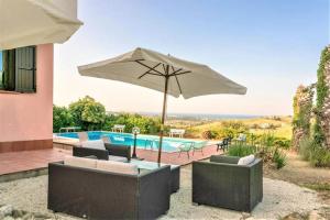 um pátio com um guarda-sol e cadeiras e uma piscina em Villa Rosè - Natura vista mare - Narramondo Villas em Cologna