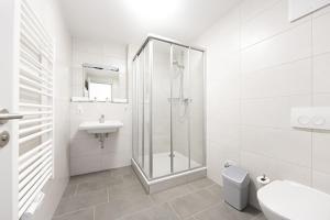 a white bathroom with a shower and a sink at Hotel garni Milseburg in Hilders