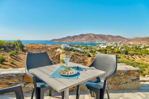 a table with a glass of wine and a plate of food at Oceania House with sea view in Ano Syros
