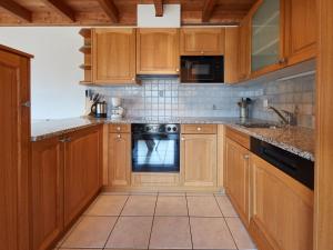 una cocina con armarios de madera y horno negro en Apartment Les Cîmes 8 by Interhome en Les Collons