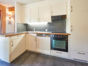 a kitchen with white cabinets and a stove at Chalet Hiboux by Interhome in Les Collons