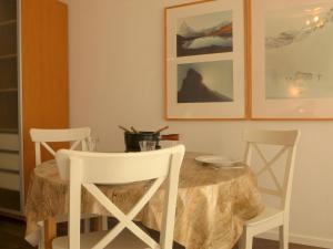 einem Esstisch mit weißen Stühlen und einem Tisch mit in der Unterkunft Apartment Select by Interhome in Zermatt