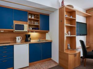 eine kleine Küche mit blauen Schränken und einer Mikrowelle in der Unterkunft Apartment Harrachovka - HRA102 by Interhome in Harrachov