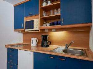 een kleine keuken met blauwe kasten en een wastafel bij Apartment Harrachovka - HRA102 by Interhome in Harrachov