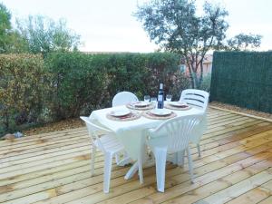 une table et des chaises blanches sur une terrasse en bois dans l'établissement Holiday Home Mer Indigo-12 by Interhome, à Saint Pierre La Mer