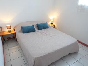 a bedroom with a bed with two blue pillows at Holiday Home Les Sentolines by Interhome in Saint Pierre La Mer