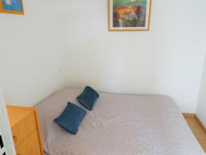 małe łóżko z 2 niebieskimi poduszkami w obiekcie Apartment Les Balcons de la Méditerranée-2 by Interhome w mieście Narbonne-Plage