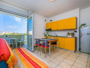 cocina con armarios amarillos y mesa con comedor en Apartment Robinia-Pinetine-3 by Interhome, en Duna Verde