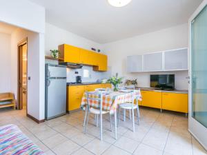 cocina con armarios amarillos, mesa y sillas en Apartment Robinia-Pinetine-4 by Interhome, en Duna Verde