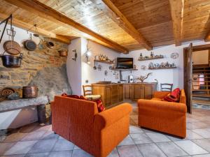 een woonkamer met 2 oranje stoelen en een stenen muur bij Holiday Home Casa Ivan by Interhome in Noasca