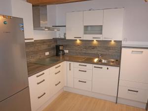 a kitchen with white cabinets and a stainless steel refrigerator at Apartment Gruber by Interhome in Flaurling