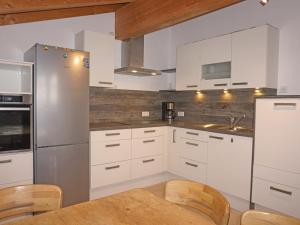 cocina con armarios blancos y mesa de madera en Apartment Gruber by Interhome, en Flaurling