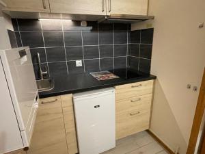 una pequeña cocina con una pared de azulejos negros en Apartment Le Savoisien by Interhome en Chamonix-Mont-Blanc