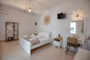 a white bedroom with a bed and a chair at Aspro Phos Santorini Hotel in Perissa