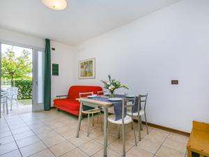 sala de estar con sofá rojo, mesa y sillas en Apartment Robinia-Pinetine-2 by Interhome, en Duna Verde