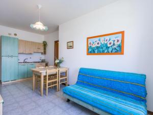 een woonkamer met een blauwe bank en een keuken bij Apartment Albatros-1 by Interhome in Caorle