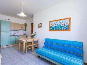 a living room with a blue couch and a kitchen at Apartment Albatros-1 by Interhome in Caorle