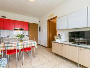 cocina con armarios rojos, mesa y sillas en Apartment Robinia-Pinetine-1 by Interhome, en Duna Verde
