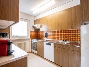 a kitchen with wooden cabinets and a sink at Apartment Chesa Clüs 6 by Interhome in Zuoz