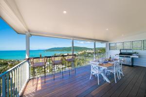 balkon ze stołem i krzesłami oraz oceanem w obiekcie South Hamptons Beach House w mieście Airlie Beach