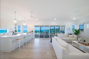 a kitchen and living room with white furniture and the ocean at South Hamptons Beach House in Airlie Beach